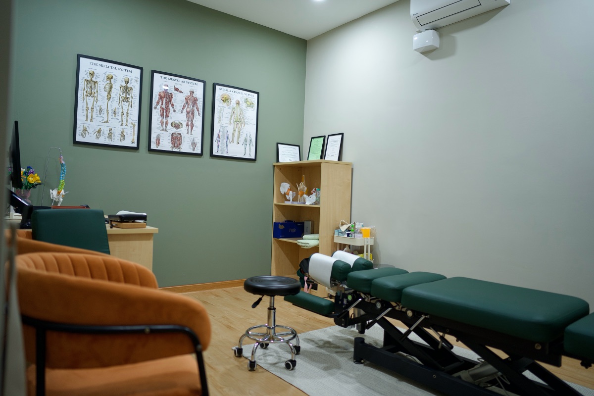 Treatment room at ChiroPlus with adjustment table and anatomy charts